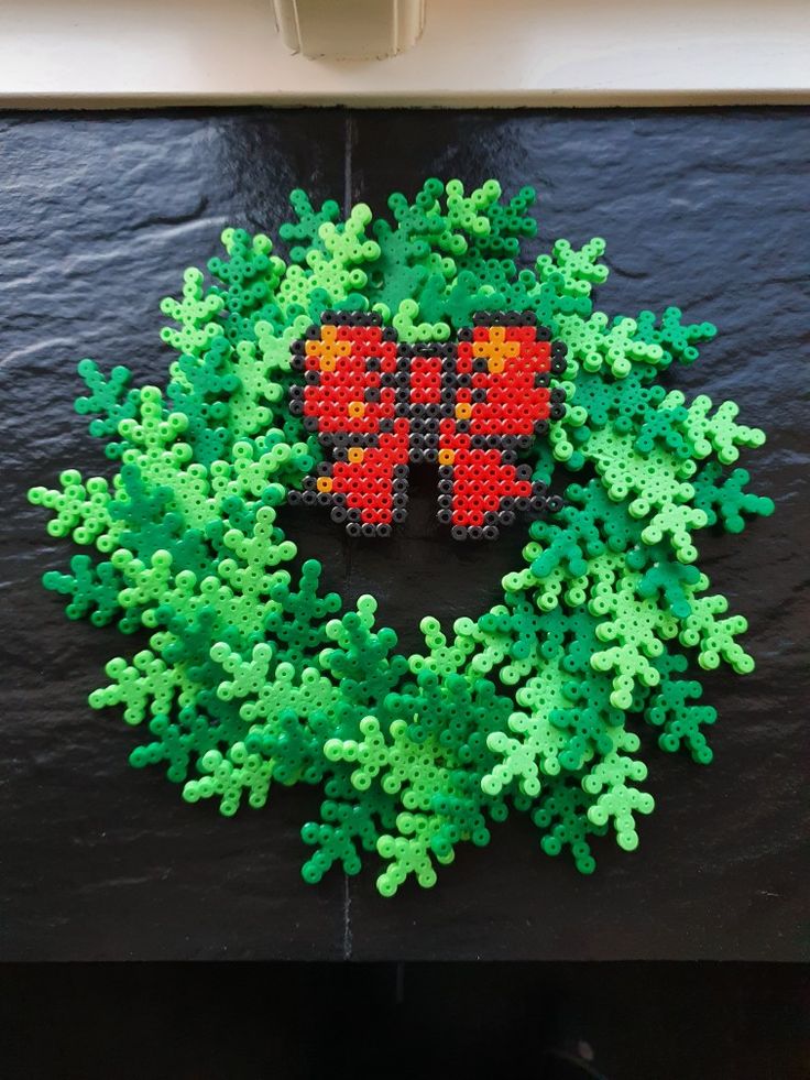 a cross - stitch christmas wreath made out of plastic beads