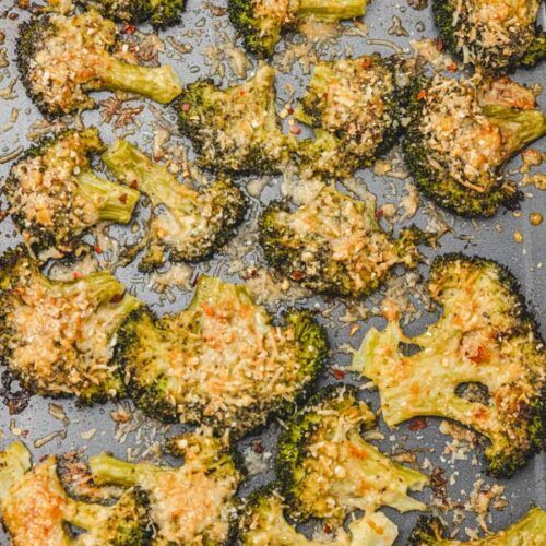 cooked broccoli florets with parmesan sprinkles on a baking sheet