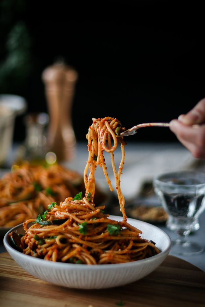 someone is eating spaghetti from a white bowl