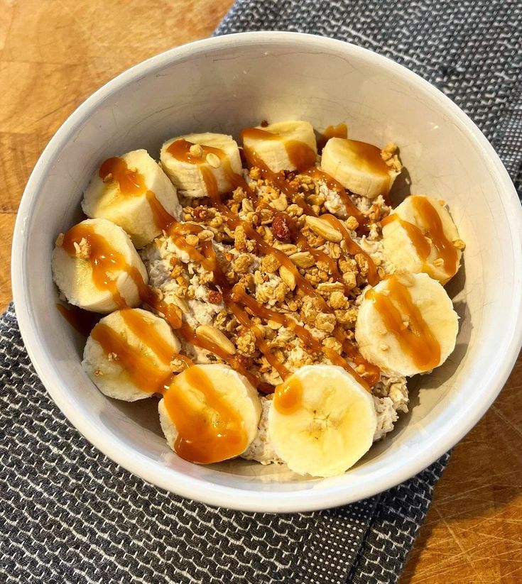 a white bowl filled with oatmeal and sliced bananas on top of a table