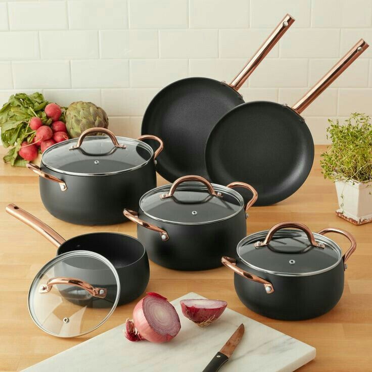 an assortment of pots and pans sitting on a table with tomatoes next to them