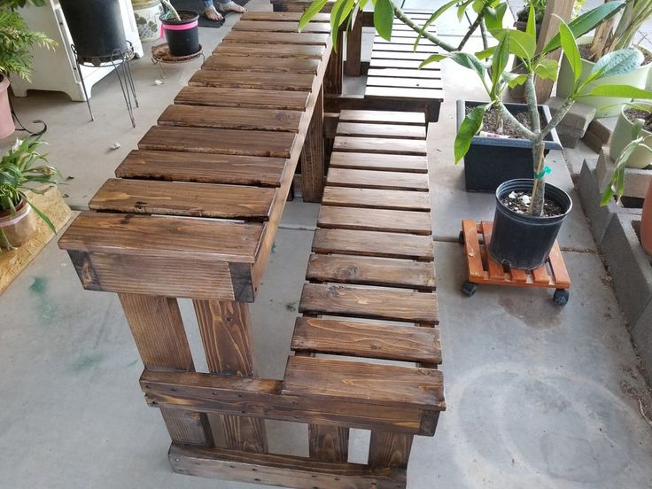 a wooden bench sitting next to a potted plant on top of a cement floor