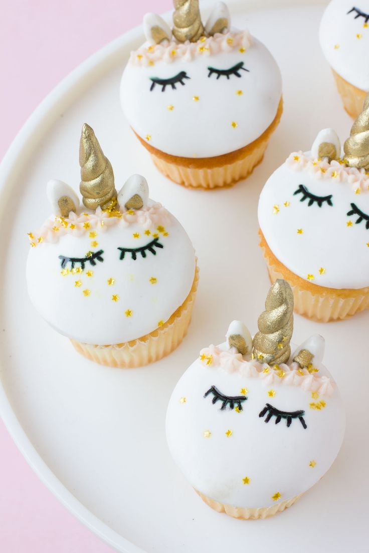 three cupcakes with white frosting and gold decorations on them are sitting on a plate