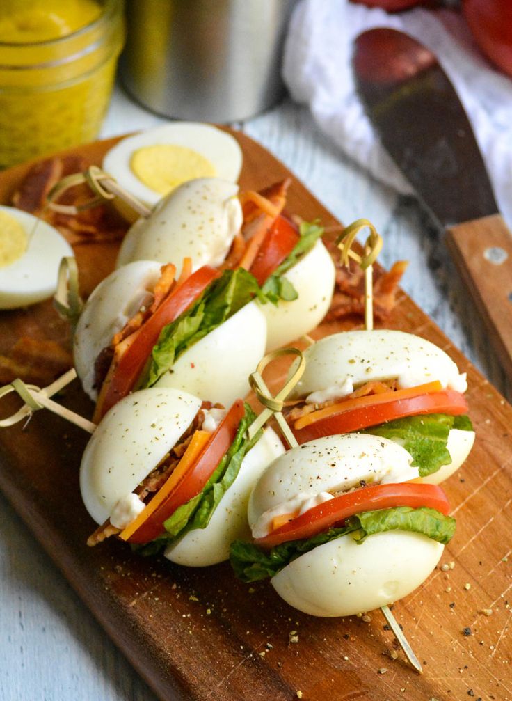 a wooden cutting board topped with sandwiches and hard boiled eggs