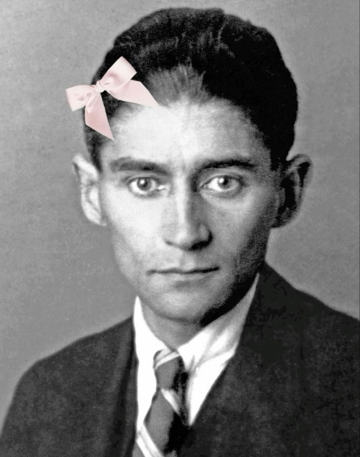 a black and white photo of a man with a pink bow in his hair, wearing a suit