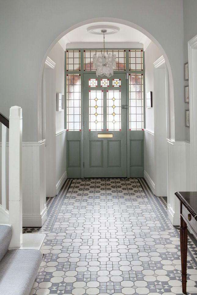 an arched doorway with stained glass windows and tiled flooring is flanked by a staircase