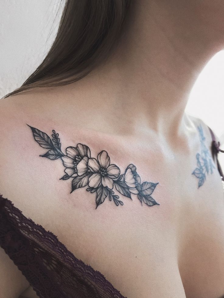 a woman's shoulder with flowers on it and leaves in the middle of her chest