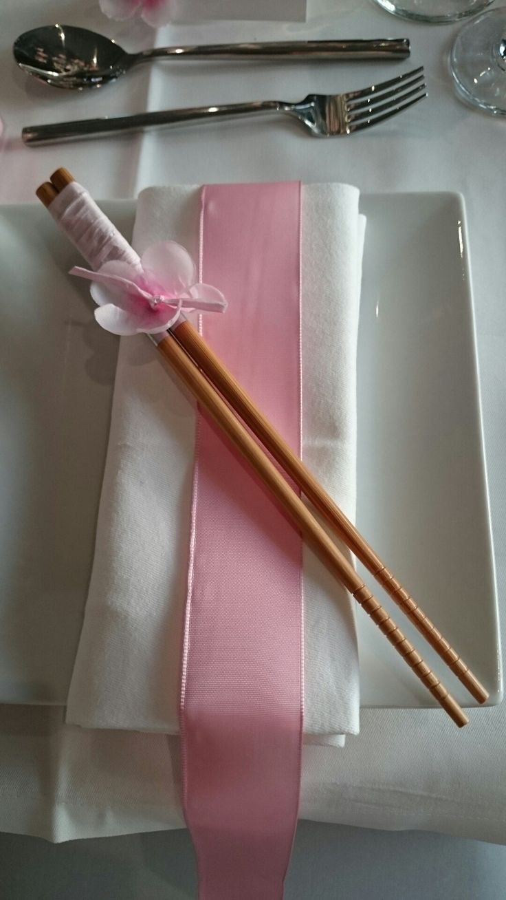 two pink and white napkins on top of a plate with utensils next to each other