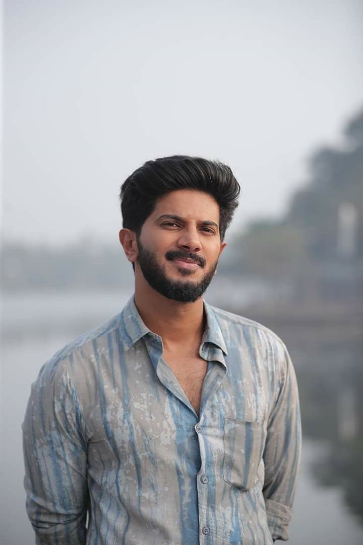 a man standing in front of a body of water wearing a blue and white shirt