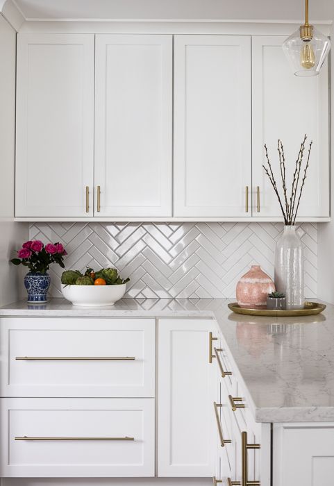 a white kitchen with marble counter tops and gold trim on the cabinet doors is shown