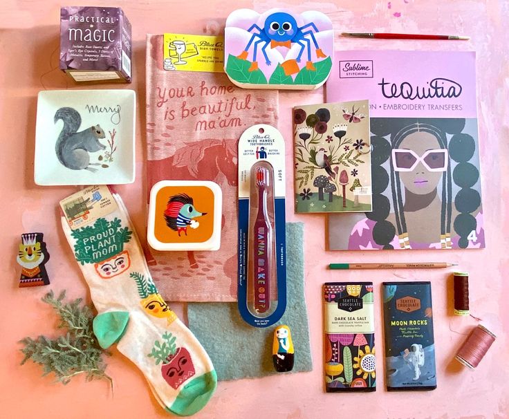 various items are laid out on top of a pink surface, including books and pens