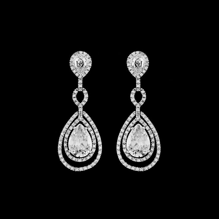 a pair of white gold and diamond earrings with pear shaped diamonds on each earring