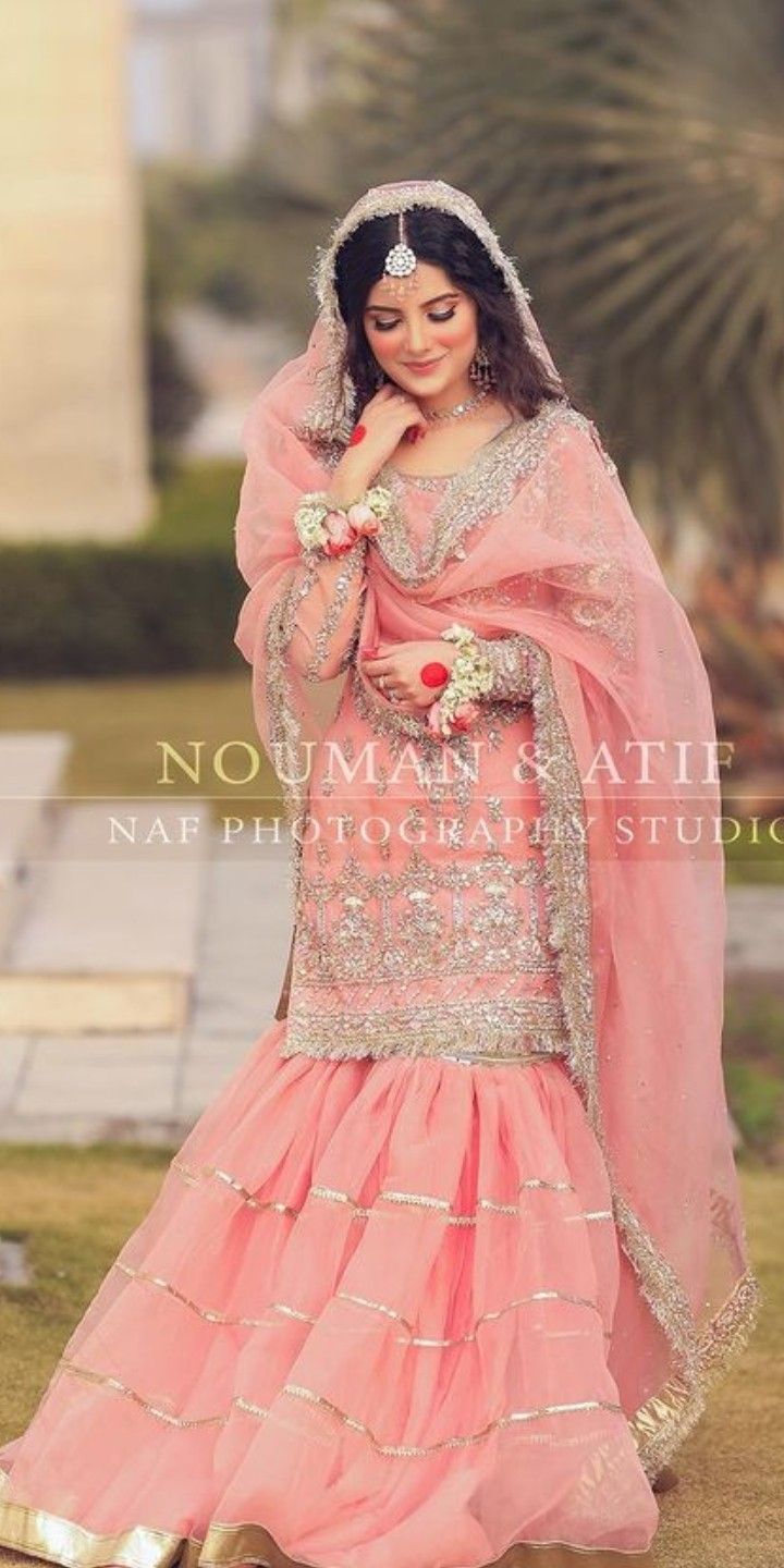 a woman in a pink dress posing for the camera with her hand on her chin