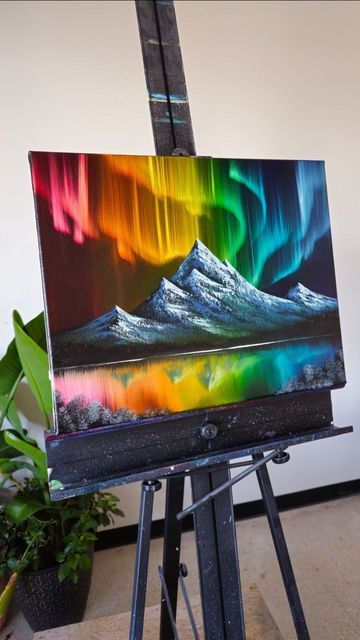 an easel with a painting on it that has the aurora lights in the sky