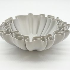 a white bowl that is shaped like an abstract flower arrangement with wavy lines on the bottom