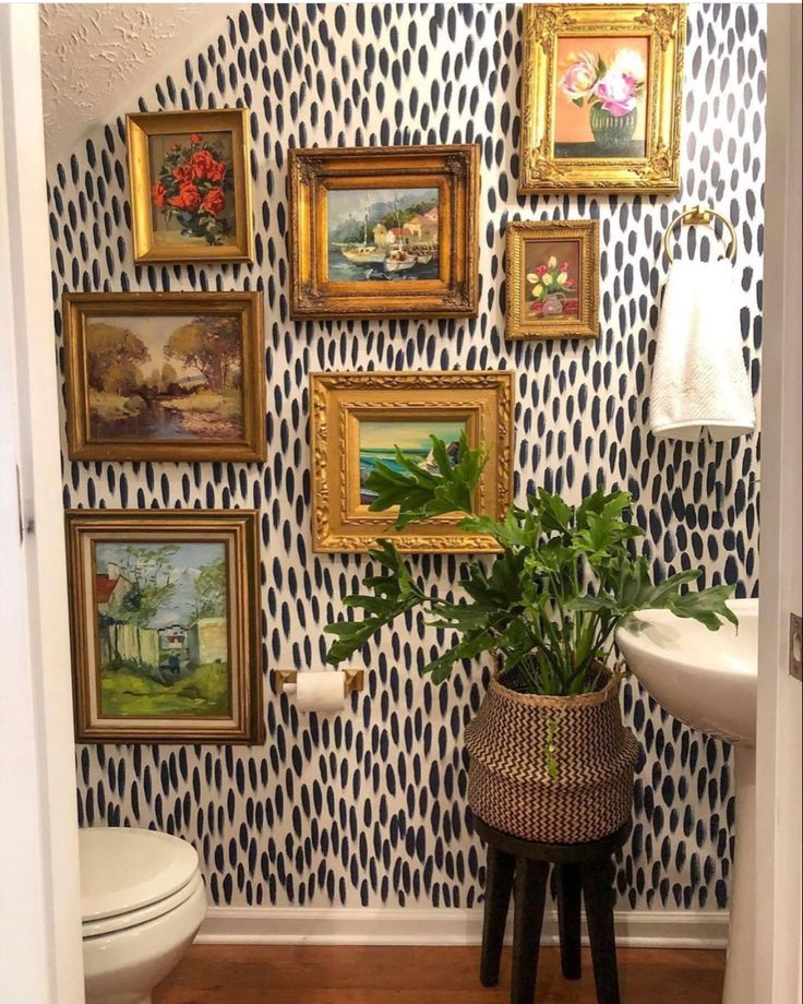 a bathroom with pictures on the wall and a potted plant in front of it