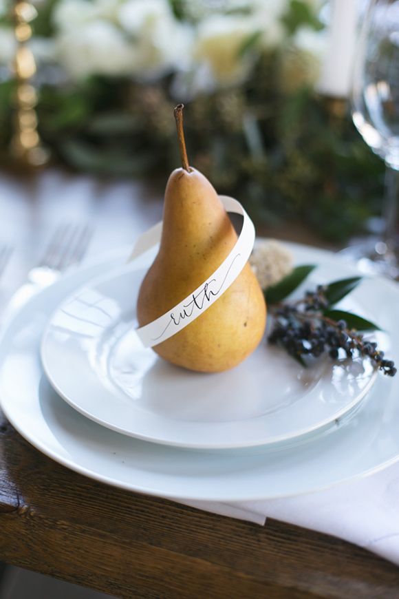 a white plate topped with a pear on top of a wooden table