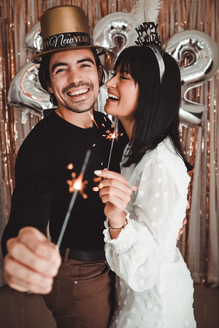 a man and woman standing next to each other holding sparklers