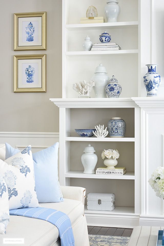 a living room filled with white furniture and lots of blue and white decor on top of it