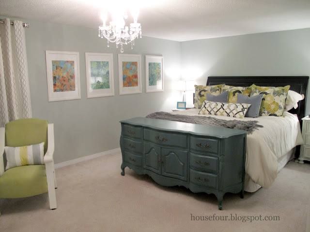 a bed room with a neatly made bed and a chandelier hanging from the ceiling