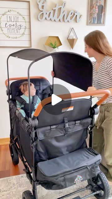 a woman standing next to a baby in a stroller with another child sitting in it