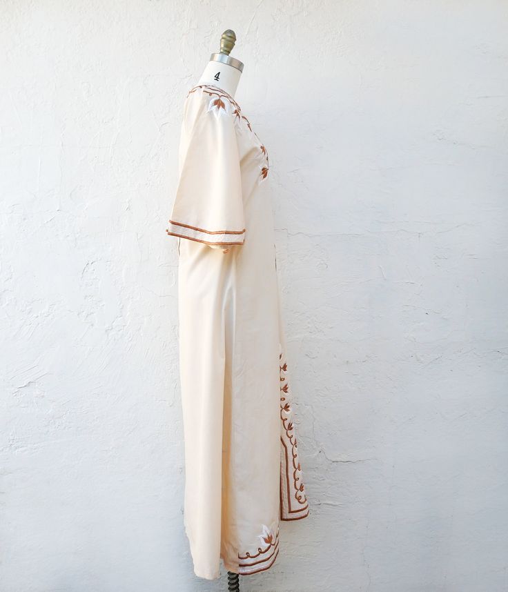 70's Ivory cotton kaftan embroidered in white and tan. This pretty boho maxi dress has elbow length bell sleeves. There are no darts. It is fitted at the waist and zips up the back. Size small fits like a current size 4 Measurements with room for comfort: Bust up to: 33 inches Waist up to: 30 inches Hips up to: 36 inches Exact measurements taken flat to compare to a garment which fits well: Length: 52 inches. Sleeve length:14 inches. Shoulders across the back: 16 inches. Bust: 17 inches. Waist: Beige Maxi Length Kaftan For Spring, Cream Maxi Dress With Floral Embroidery, Cream Embroidered Maxi Dress, Cream Bohemian Maxi Dress With Floral Embroidery, Bohemian Cream Maxi Dress With Floral Embroidery, Long Cream Cotton Dress, Beige Embroidered Bohemian Maxi Dress, Embroidered Cream Kaftan For Summer, Cream Embroidered Kaftan For Spring