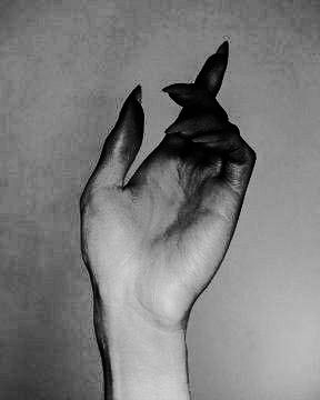 black and white photograph of a person's hand holding a small object in the air