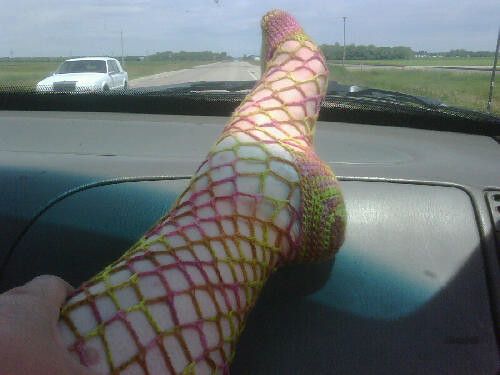 a person's legs are covered in fishnet on the dashboard of a car