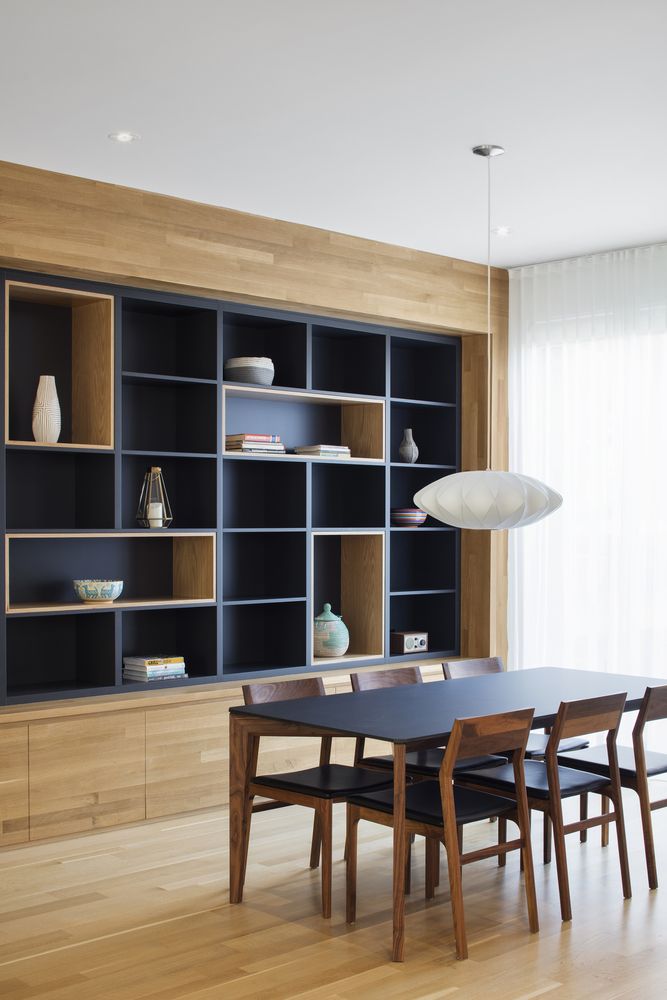 a dining room table and chairs in front of a bookshelf with wooden shelves