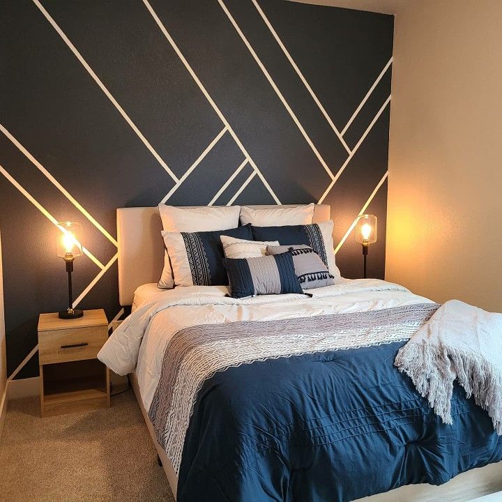 a bed with blue and white pillows in a bedroom next to two lamps on either side of the bed