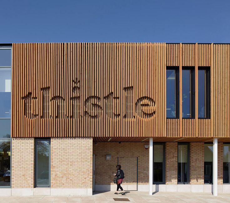 a person walking on the sidewalk in front of a building with wooden slatted facade