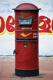 a red mailbox sitting on the side of a building next to a graffiti covered wall