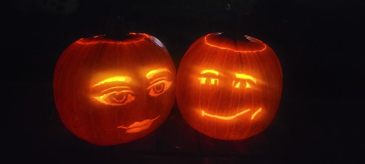 two pumpkins with faces carved into them