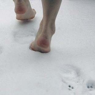 two people walking in the snow with bare feet