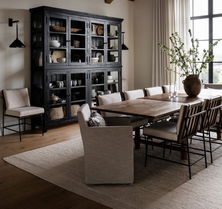 a dining room table with chairs and a bookcase in front of a window that looks out onto the outdoors