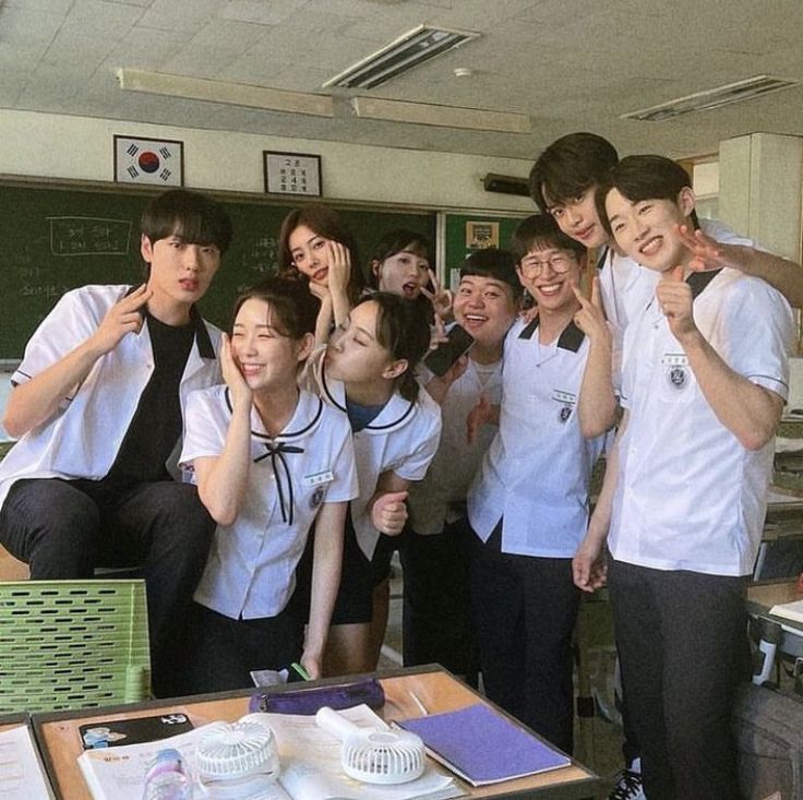 a group of young people standing next to each other in front of a blackboard