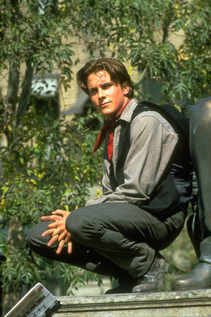 a young man sitting on top of a statue