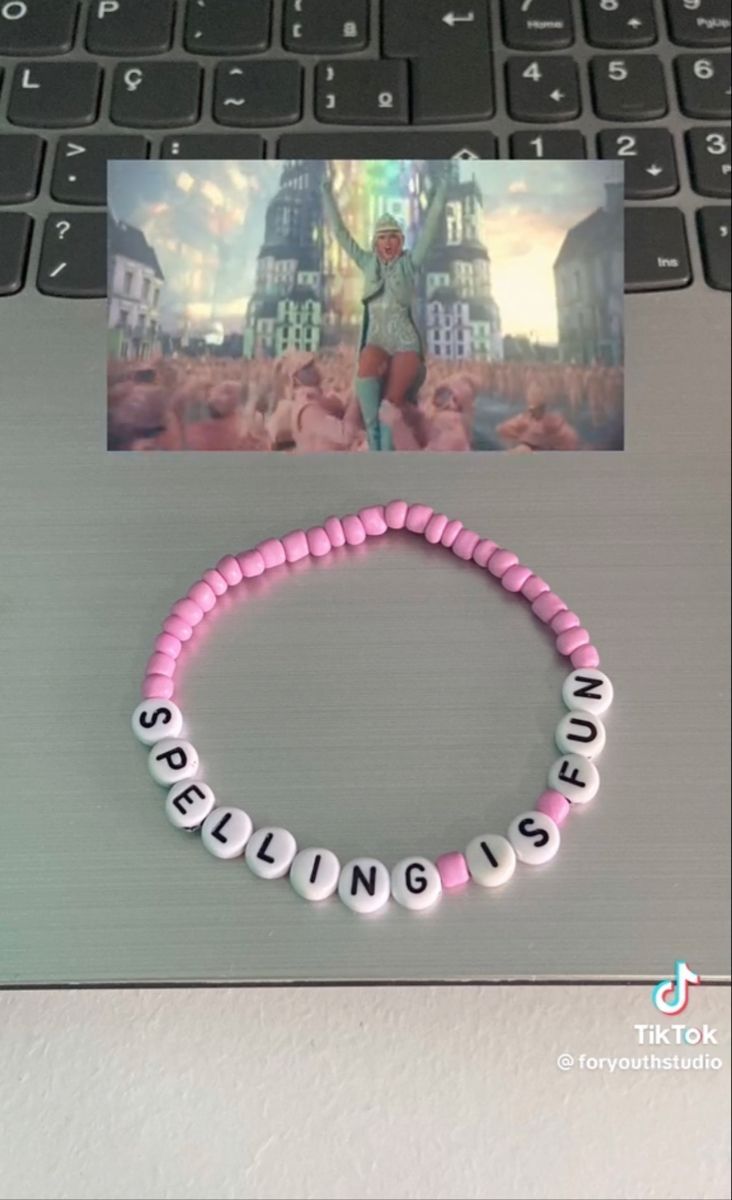 a pink beaded bracelet sitting on top of a laptop computer next to a photo