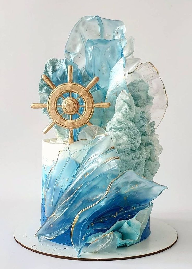 there is a blue and white cake with waves on the bottom that has a ship's wheel