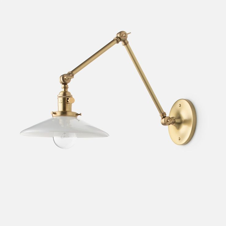 an antique brass wall light with a white glass shade on the arm and two arms