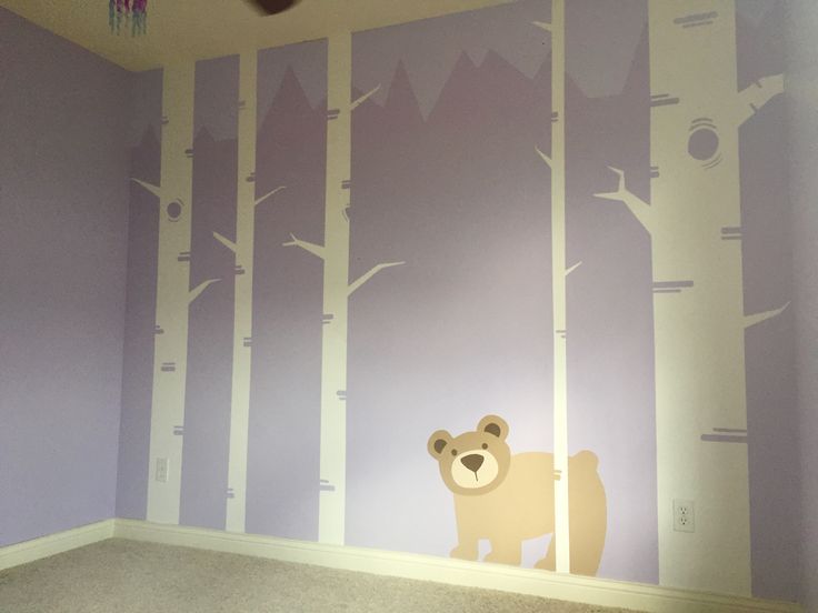 there is a bear and tree mural on the wall in this child's room