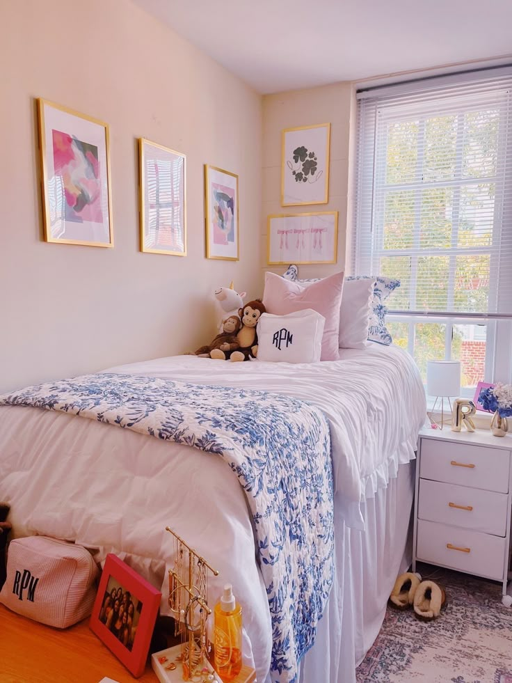 a white bed sitting next to a window with pictures on the wall above it in a bedroom