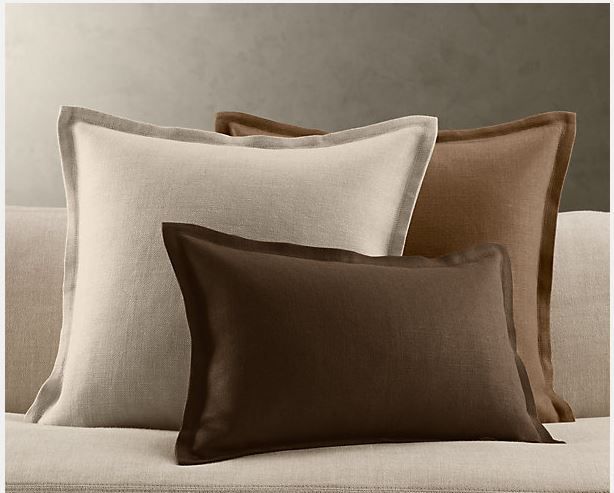 three pillows on a couch in front of a black wall