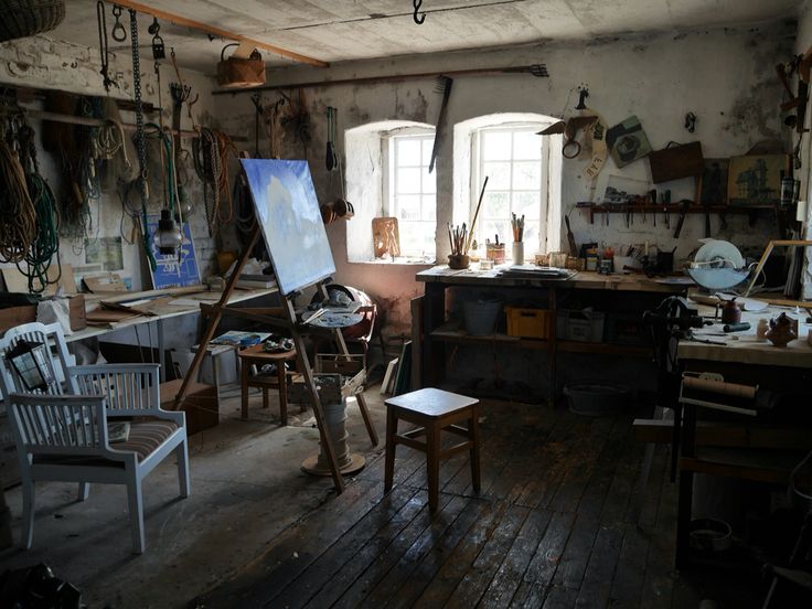 an artist's studio with chairs and paintings