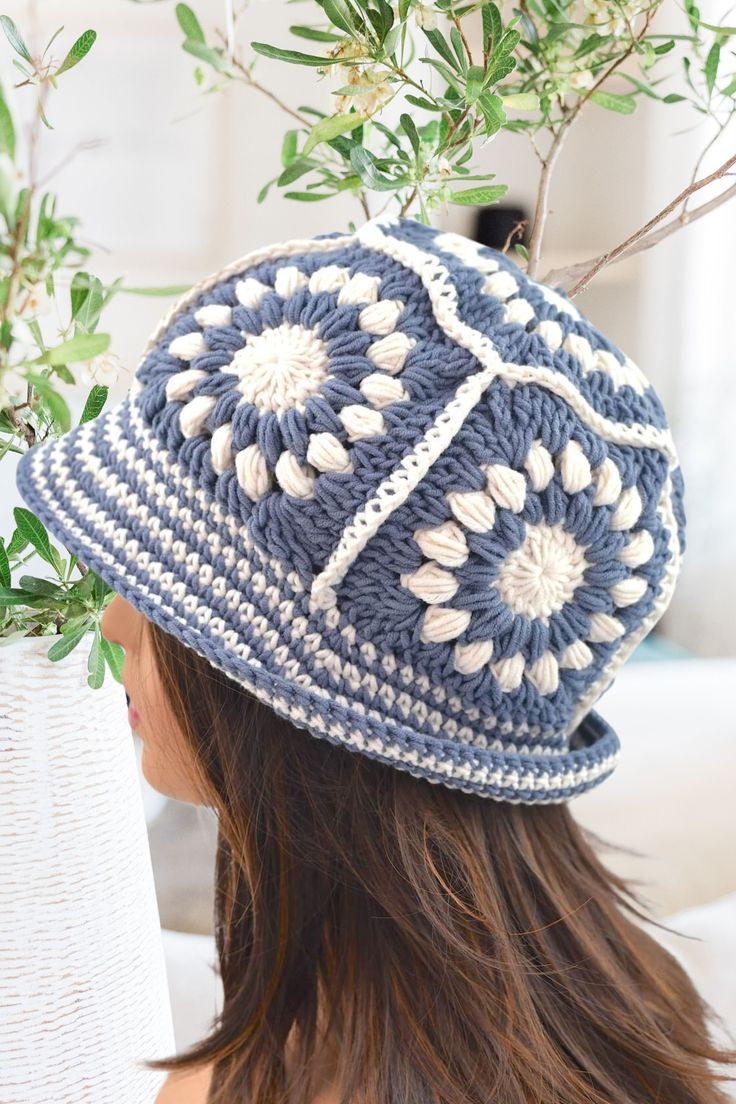 a woman wearing a blue crocheted hat with white flowers on the brim