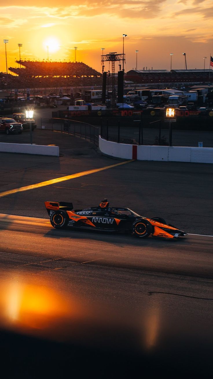 a race car driving down the track at sunset