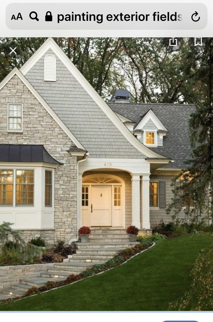 a stone house with white trim and gray shingles on the front door, steps leading up to it