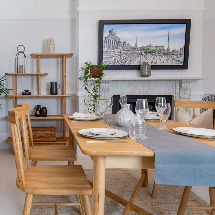 a dining room table set for four with plates and wine glasses on the placemats