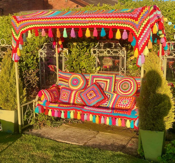 a couch covered in crochet sitting on top of a lush green park area