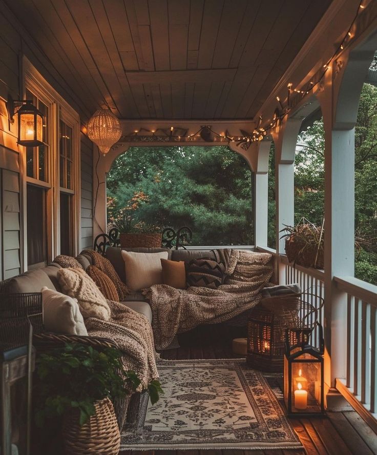 a porch with lights strung from the ceiling and pillows on the couch, along with lanterns